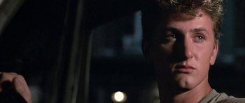 Movie still from “At Close Range” (1986), directed by James Foley – A man's face in the dark; Close Up shot, Over the shoulder angle