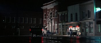 Movie still from “At Close Range” (1986), directed by James Foley – People walking on the sidewalk in front of a building at night; Extreme Wide shot, Low angle