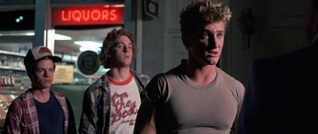 Movie still from “At Close Range” (1986), directed by James Foley – Two young men standing next to each other on the street; Medium shot, Low angle