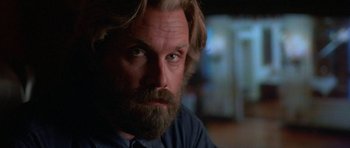 Movie still from “At Close Range” (1986), directed by James Foley – A person with long hair and a beard; Close Up shot, Low angle