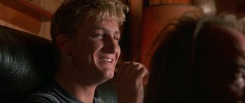 Movie still from “At Close Range” (1986), directed by James Foley – A young man smiling while sitting in front of a mirror; Close Up shot, Over the shoulder angle