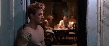 Movie still from “At Close Range” (1986), directed by James Foley – A group of people sitting around a table; Medium shot, Over the shoulder angle