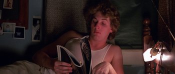 Movie still from “At Close Range” (1986), directed by James Foley – A man reading a magazine in bed at night; Close Up shot, High angle