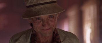 Movie still from “At Close Range” (1986), directed by James Foley – An older man wearing a hat and smiling for the camera; Close Up shot, Low angle