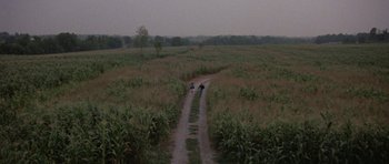 Movie still from “At Close Range” (1986), directed by James Foley – Two people riding a motorcycle down a dirt road; Extreme Wide shot, High angle