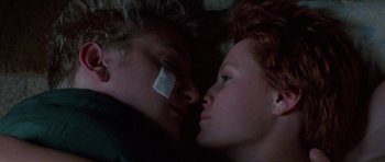 Movie still from “At Close Range” (1986), directed by James Foley – A man and a woman laying on the ground; Close Up shot, Overhead angle