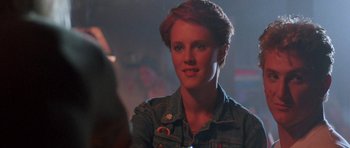 Movie still from “At Close Range” (1986), directed by James Foley – A woman with red hair is smiling for the camera; Close Up shot, Over the shoulder angle