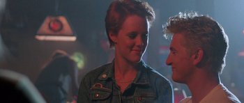 Movie still from “At Close Range” (1986), directed by James Foley – A woman in a jean jacket talking to another person; Close Up shot, Over the shoulder angle