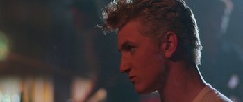 Movie still from “At Close Range” (1986), directed by James Foley – A person's face in a dark room; Close Up shot, Over the shoulder angle