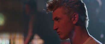 Movie still from “At Close Range” (1986), directed by James Foley – A person's face in a dark room; Close Up shot, Over the shoulder angle