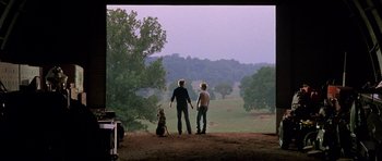 Movie still from “At Close Range” (1986), directed by James Foley – Two people and a dog standing on a dirt hill; Wide shot, Low angle