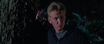Movie still from “At Close Range” (1986), directed by James Foley – A man holding a cell phone up to his ear; Close Up shot, Low angle
