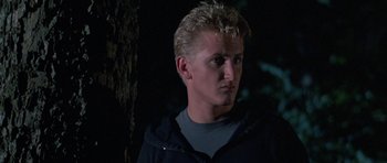 Movie still from “At Close Range” (1986), directed by James Foley – A man with blonde spiky hair standing in the dark; Close Up shot, Low angle