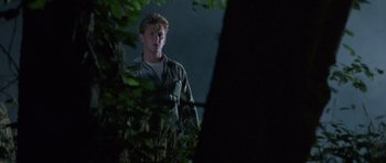 Movie still from “At Close Range” (1986), directed by James Foley – A man standing next to a tree in the dark; Medium shot, Low angle