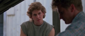 Movie still from “At Close Range” (1986), directed by James Foley – A man with a curly hair sitting in front of a mirror; Close Up shot, Over the shoulder angle