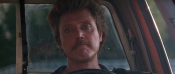 Movie still from “At Close Range” (1986), directed by James Foley – A person in a car; Close Up shot, Low angle