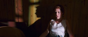 Movie still from “At Close Range” (1986), directed by James Foley – A woman sitting in the sunlight with her hand on her face; Medium shot, Low angle