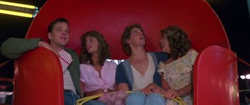 Movie still from “At Close Range” (1986), directed by James Foley – A group of young people sitting on top of a red couch; Medium shot, Low angle