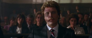 Movie still from “At Close Range” (1986), directed by James Foley – A man in a black suit and a red and white striped tie; Close Up shot, Low angle