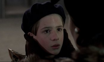 Movie still from “Au revoir les enfants” (1987), directed by Louis Malle – A young boy wearing a hat looking at the camera; Close Up shot, Over the shoulder angle