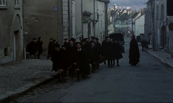 Movie still from “Au revoir les enfants” (1987), directed by Louis Malle – A group of people walking down a street; Extreme Wide shot, High angle