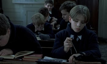 Movie still from “Au revoir les enfants” (1987), directed by Louis Malle – A group of young people sitting at a desk; Medium shot, High angle