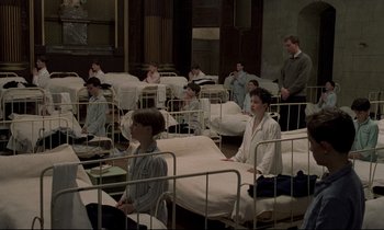 Movie still from “Au revoir les enfants” (1987), directed by Louis Malle – A group of people sitting in a hospital bed; Wide shot, High angle
