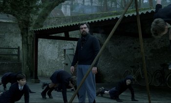 Movie still from “Au revoir les enfants” (1987), directed by Louis Malle – A group of people are playing a game in a courtyard; Wide shot, Low angle