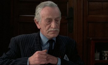 Movie still from “Au revoir les enfants” (1987), directed by Louis Malle – An older man wearing a suit and tie; Close Up shot, Low angle