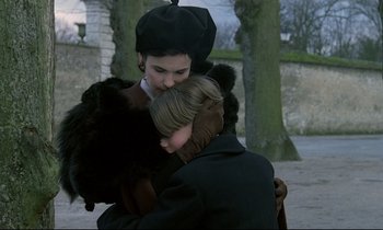 Movie still from “Au revoir les enfants” (1987), directed by Louis Malle – A woman is hugging a man in front of trees; Medium shot, High angle