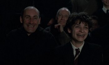 Movie still from “Au revoir les enfants” (1987), directed by Louis Malle – A group of men in suits smiling for the camera; Medium shot, High angle