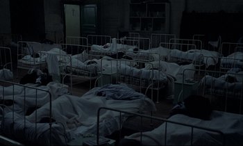 Movie still from “Au revoir les enfants” (1987), directed by Louis Malle – A room filled with beds covered in blankets; Wide shot, High angle