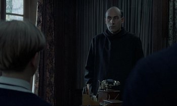 Movie still from “Au revoir les enfants” (1987), directed by Louis Malle – A man standing in front of a mirror in a room; Medium shot, Over the shoulder angle