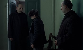Movie still from “Au revoir les enfants” (1987), directed by Louis Malle – A group of men standing around a room; Medium shot, Over the shoulder angle