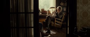 Movie still from “August: Osage County” (2013), directed by John Wells – An older man sitting in a chair reading a book; Wide shot, Over the shoulder angle