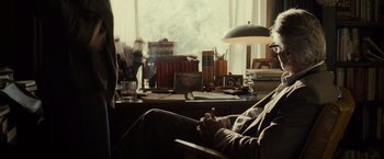 Movie still from “August: Osage County” (2013), directed by John Wells – A man sitting at a desk in front of a window; Medium shot, Over the shoulder angle