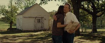 Movie still from “August: Osage County” (2013), directed by John Wells – A man and a woman hugging in front of an old house; Medium shot, Over the shoulder angle