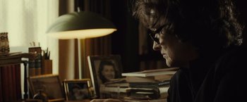 Movie still from “August: Osage County” (2013), directed by John Wells – An older woman sitting at a table looking at a book; Close Up shot, Over the shoulder angle