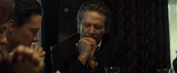 Movie still from “August: Osage County” (2013), directed by John Wells – An older man sitting at a table with his hands clasped together; Close Up shot, Low angle