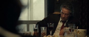 Movie still from “August: Osage County” (2013), directed by John Wells – An older man sitting at a dinner table with a glass of wine; Close Up shot, Over the shoulder angle