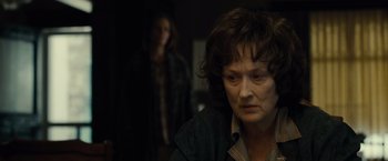 Movie still from “August: Osage County” (2013), directed by John Wells – A woman in a dark room with a woman in the background; Close Up shot, Over the shoulder angle