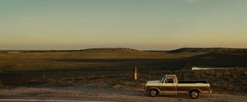 Movie still from “August: Osage County” (2013), directed by John Wells – A woman standing in a field next to a truck; Extreme Wide shot, Over the shoulder angle