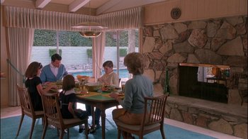 Movie still from “Auto Focus” (2002), directed by Paul Schrader – A group of people sitting around a table eating food; Wide shot, High angle