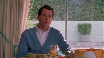 Movie still from “Auto Focus” (2002), directed by Paul Schrader – A man sitting at a table with a plate of food in front of him; Medium shot, Over the shoulder angle