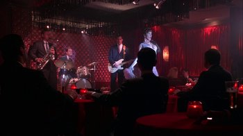 Movie still from “Auto Focus” (2002), directed by Paul Schrader – A group of people playing music in a red room; Wide shot, Over the shoulder angle