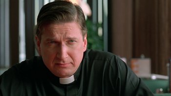 Movie still from “Auto Focus” (2002), directed by Paul Schrader – A man wearing a priest's collar and a clerical collar; Close Up shot, Low angle