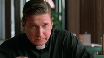 Movie still from “Auto Focus” (2002), directed by Paul Schrader – A man wearing a priest's collar and a clerical collar; Close Up shot, Low angle