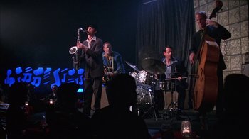 Movie still from “Auto Focus” (2002), directed by Paul Schrader – A group of men playing musical instruments on a stage; Wide shot, Low angle