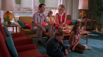 Movie still from “Auto Focus” (2002), directed by Paul Schrader – A group of people sitting on the floor of a living room; Wide shot, High angle