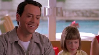 Movie still from “Auto Focus” (2002), directed by Paul Schrader – A man sitting next to a little girl in front of a pool; Close Up shot, Over the shoulder angle